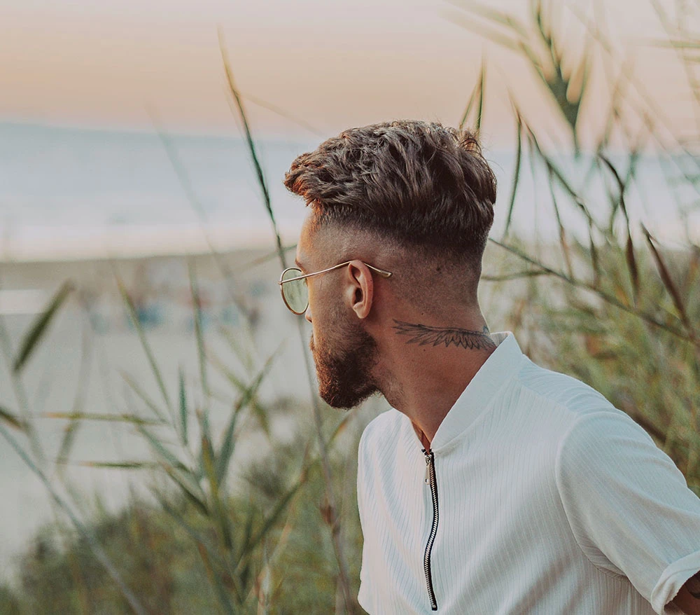 man with neck tattoo looking at ocean | Raggio Facial Plastic Surgery